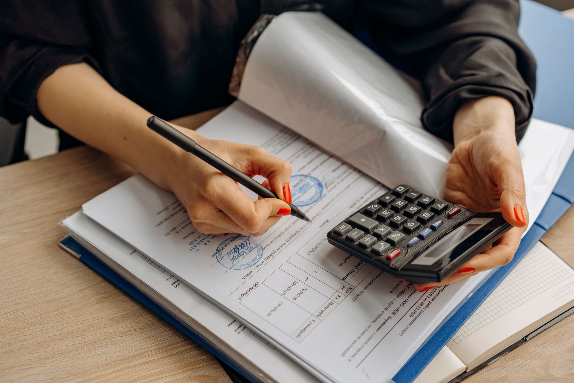An accountant using a calculator and signing paperwork, showcasing financial analysis.
