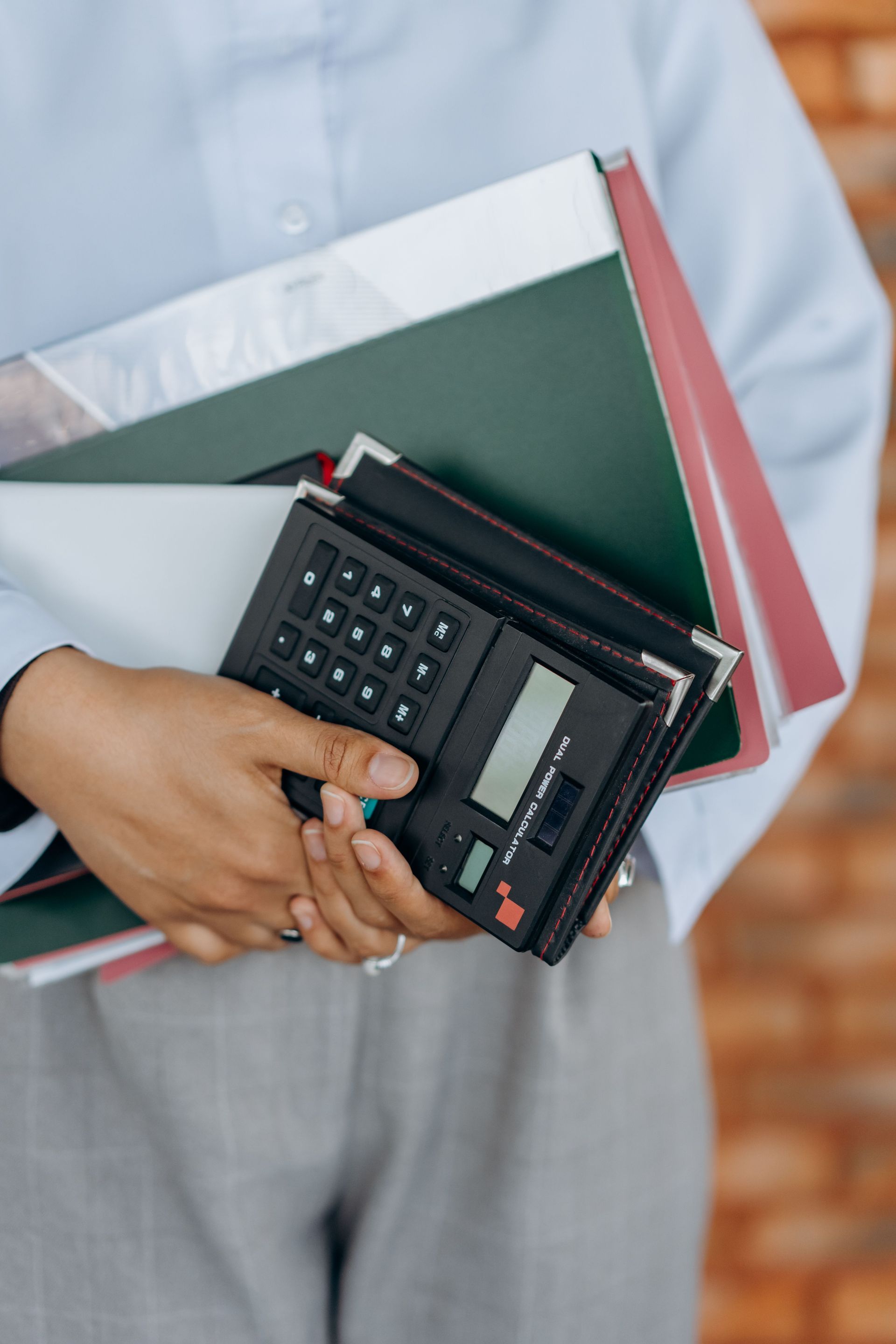 Close-up of a person holding a calculator and folders, symbolizing office work and organization.